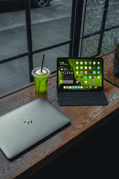 棕色木桌上绿色塑料杯旁的macbook pro